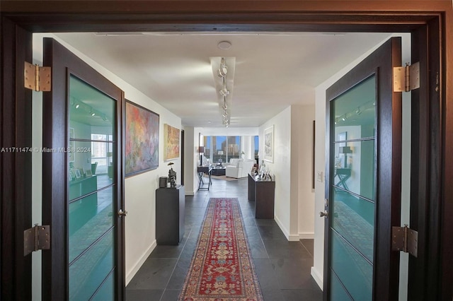 hallway with rail lighting and dark tile patterned flooring