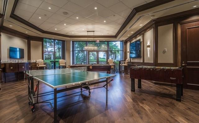 playroom featuring a raised ceiling and dark wood-type flooring