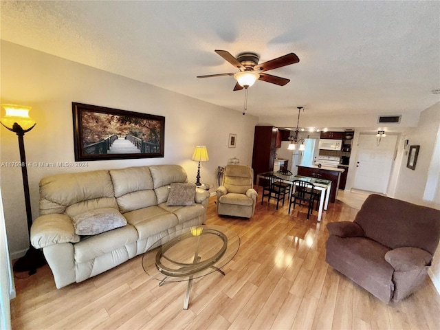 living room featuring ceiling fan, light hardwood / wood-style flooring, and a textured ceiling