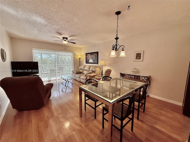 dining room featuring ceiling fan with notable chandelier, a textured ceiling, and hardwood / wood-style flooring