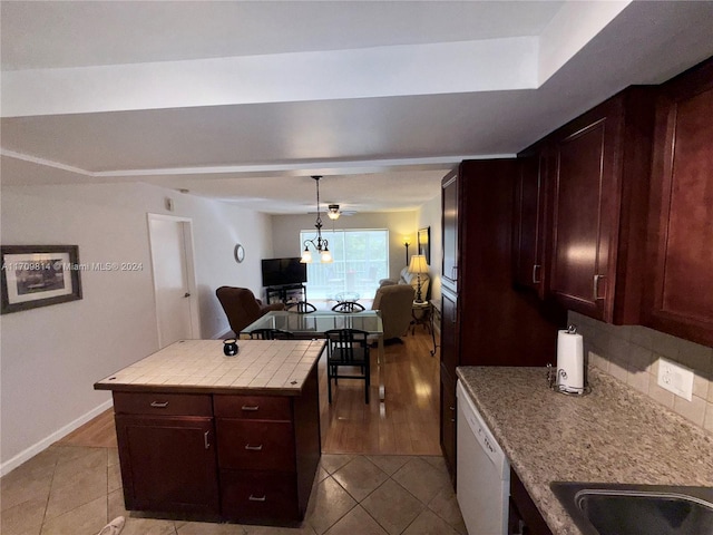 kitchen with pendant lighting, white dishwasher, light tile patterned floors, tasteful backsplash, and tile counters