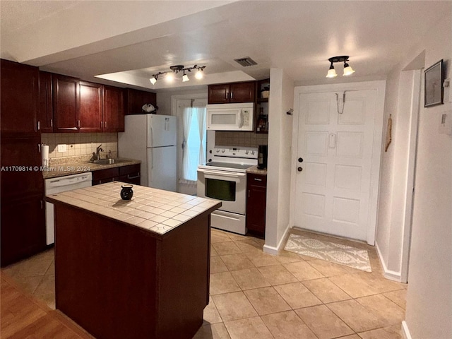 kitchen featuring a center island, white appliances, decorative backsplash, tile counters, and light tile patterned flooring