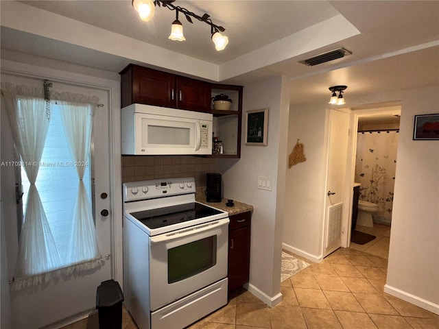 kitchen with decorative backsplash, light tile patterned floors, white appliances, and dark brown cabinetry