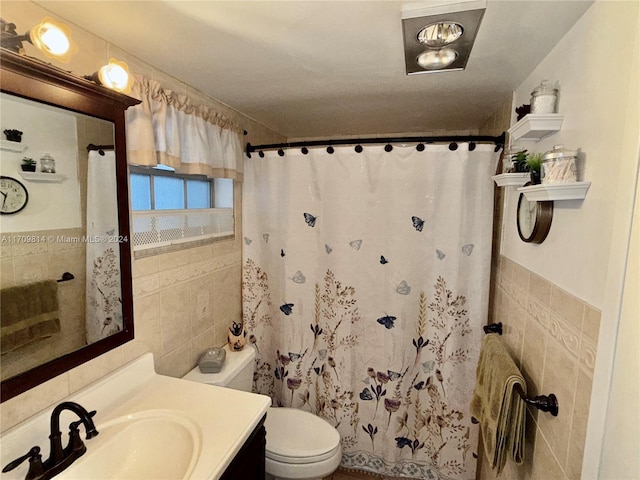 bathroom with a shower with curtain, vanity, toilet, and tile walls