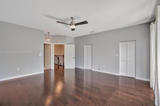 interior space featuring ceiling fan, dark hardwood / wood-style flooring, and two closets