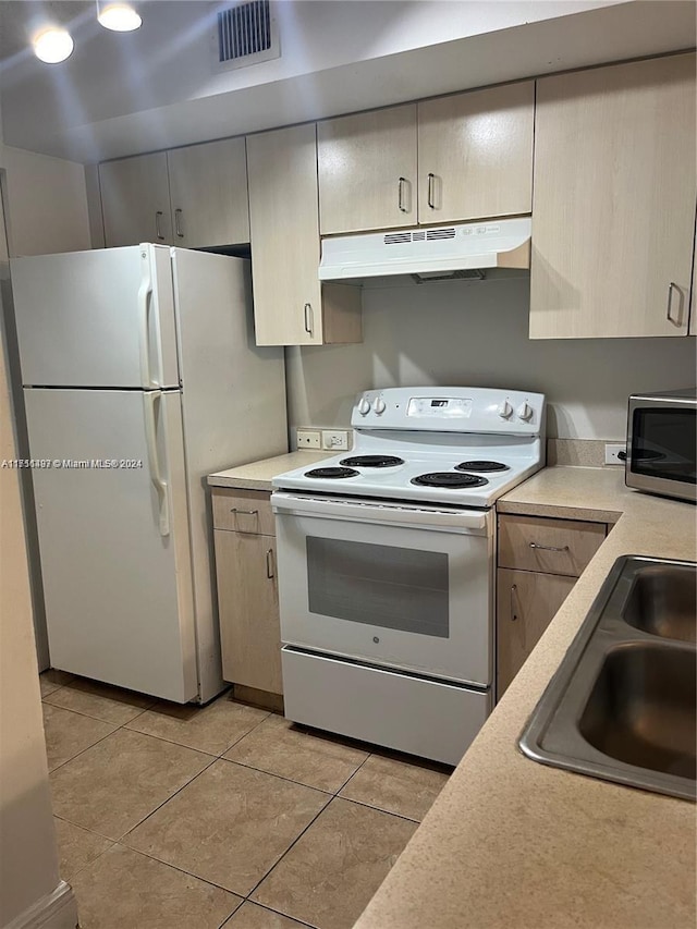 kitchen featuring light tile patterned floors, white appliances, and sink