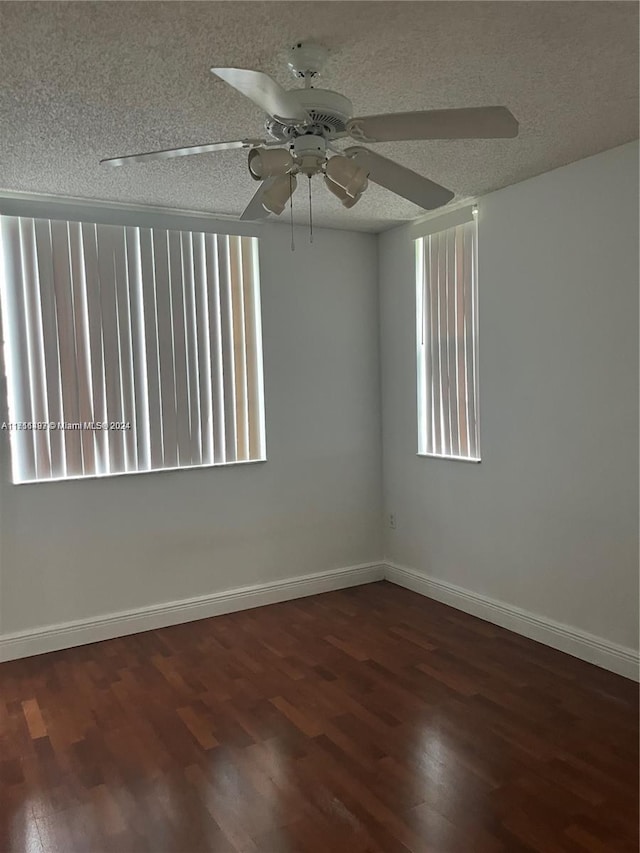 unfurnished room featuring a textured ceiling, dark hardwood / wood-style floors, and plenty of natural light