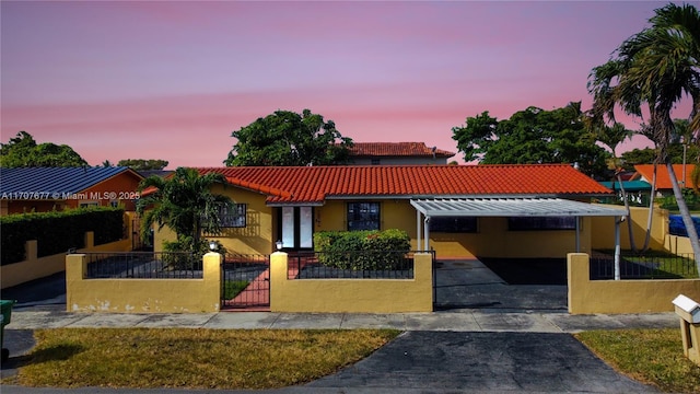 mediterranean / spanish-style house featuring a fenced front yard, a gate, a tiled roof, and stucco siding