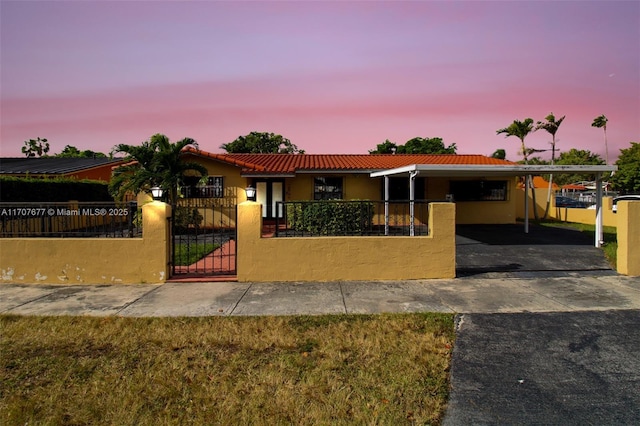 view of front of home with a fenced front yard, aphalt driveway, stucco siding, a gate, and an attached carport