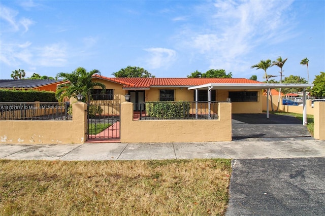 view of front of house with a fenced front yard, a tile roof, a gate, stucco siding, and a carport