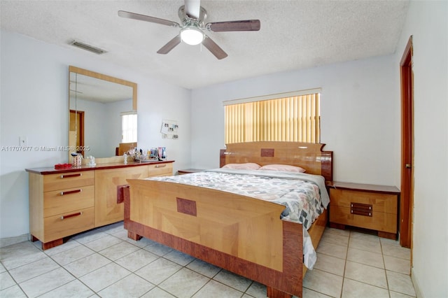 bedroom with light tile patterned floors, a ceiling fan, visible vents, and a textured ceiling