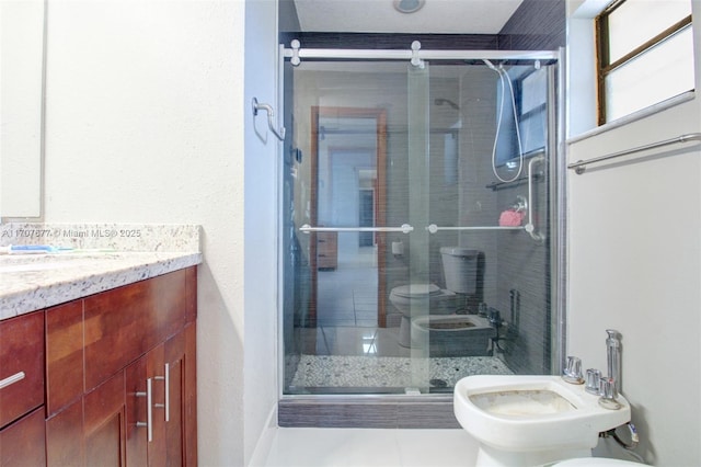 bathroom featuring toilet, a shower stall, a bidet, and vanity