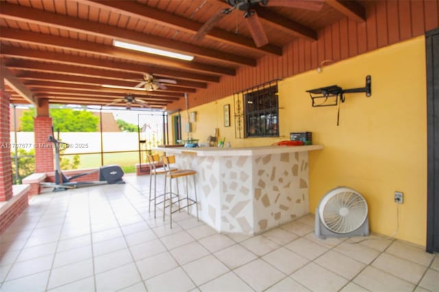 exterior space with ceiling fan, light tile patterned flooring, a breakfast bar, wood ceiling, and beamed ceiling