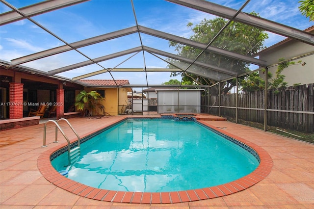 view of swimming pool featuring a lanai, a patio area, a pool with connected hot tub, and fence