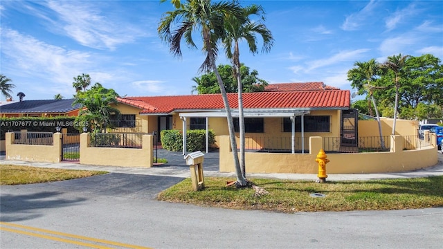 view of front of house with a fenced front yard, aphalt driveway, a tiled roof, and stucco siding