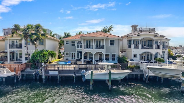 rear view of property with a patio, a balcony, a water view, a tile roof, and stucco siding