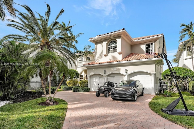 mediterranean / spanish home featuring decorative driveway, fence, a tiled roof, and stucco siding