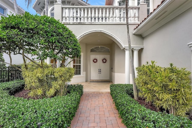 entrance to property featuring a balcony and stucco siding