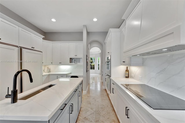 kitchen with black electric cooktop, backsplash, light stone counters, and white cabinets