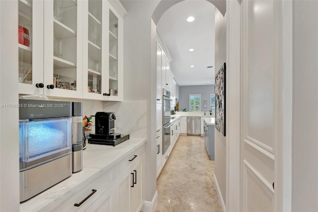 bar with white cabinetry, tasteful backsplash, stainless steel appliances, and light stone counters