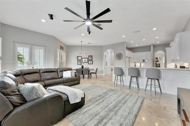 living room with arched walkways, ceiling fan with notable chandelier, visible vents, and recessed lighting