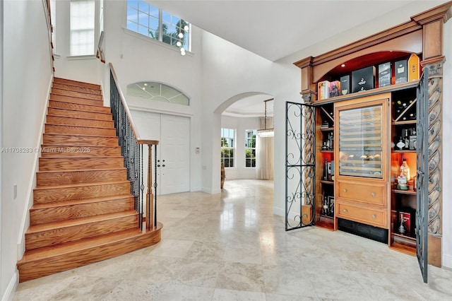 foyer entrance with arched walkways, baseboards, a high ceiling, and stairs