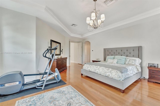 bedroom featuring wood-type flooring, ornamental molding, and a notable chandelier