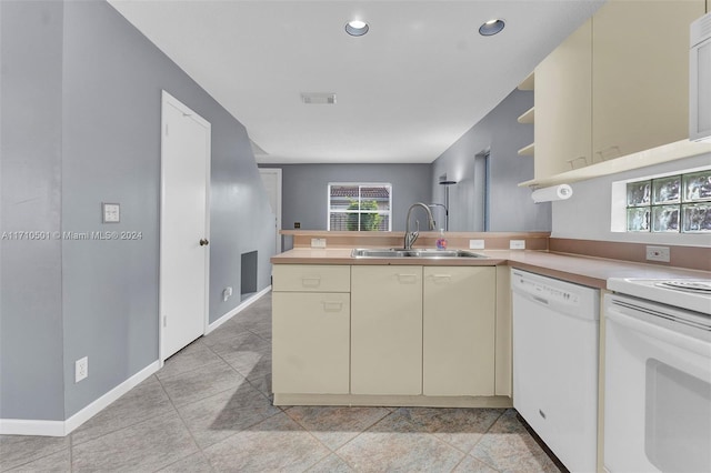 kitchen featuring cream cabinetry, kitchen peninsula, white appliances, and sink