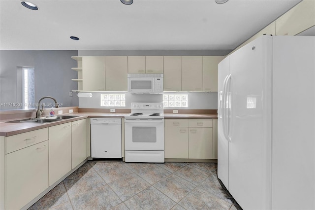 kitchen with cream cabinetry, plenty of natural light, white appliances, and sink