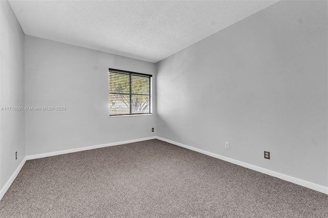 carpeted empty room featuring a textured ceiling