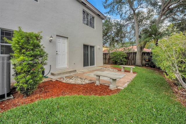 back of house featuring central air condition unit, a patio area, and a lawn