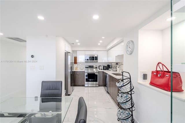 kitchen featuring sink, stainless steel appliances, backsplash, dark brown cabinets, and white cabinets