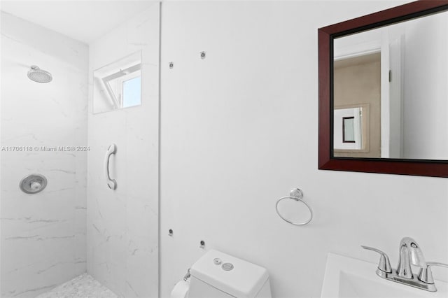 bathroom featuring sink, tiled shower, and toilet