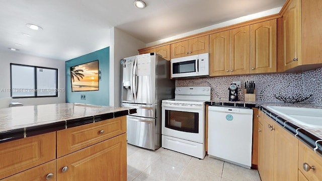 kitchen with tasteful backsplash, light tile patterned floors, white appliances, and tile counters