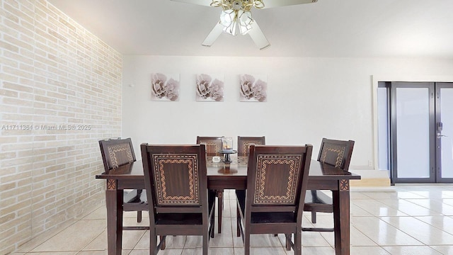 tiled dining room with french doors, ceiling fan, and brick wall