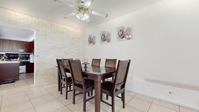 dining room featuring ceiling fan, brick wall, and light tile patterned floors