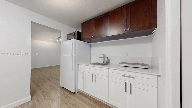 16313 SW 99th Pl, Miami, FL 33157 - kitchen with light wood finished floors, baseboards, light countertops, freestanding refrigerator, and a sink