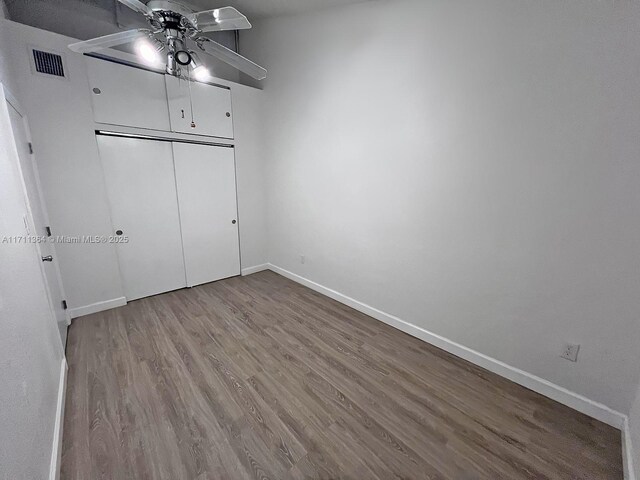 unfurnished bedroom with ceiling fan, a closet, and hardwood / wood-style floors