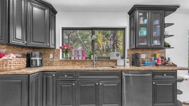 kitchen with tasteful backsplash, light stone counters, and sink