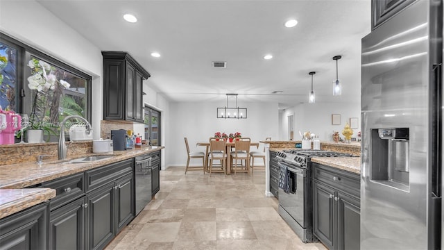 kitchen featuring backsplash, light stone counters, stainless steel appliances, sink, and pendant lighting