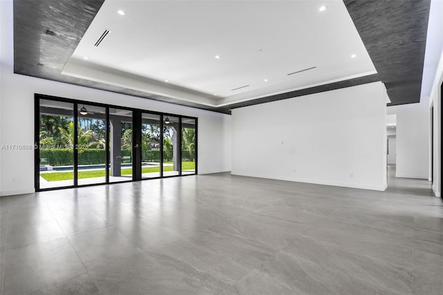 empty room featuring a raised ceiling, concrete floors, and french doors