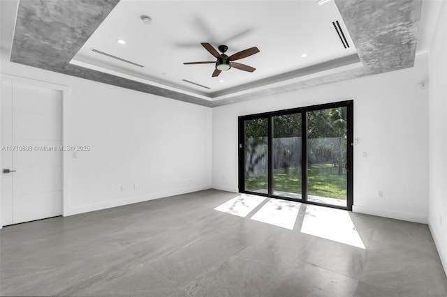 unfurnished room featuring ceiling fan, a raised ceiling, and concrete floors