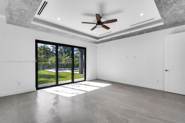 empty room with concrete flooring, ceiling fan, and a tray ceiling