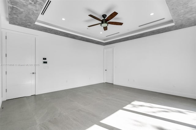 spare room with ceiling fan and a tray ceiling