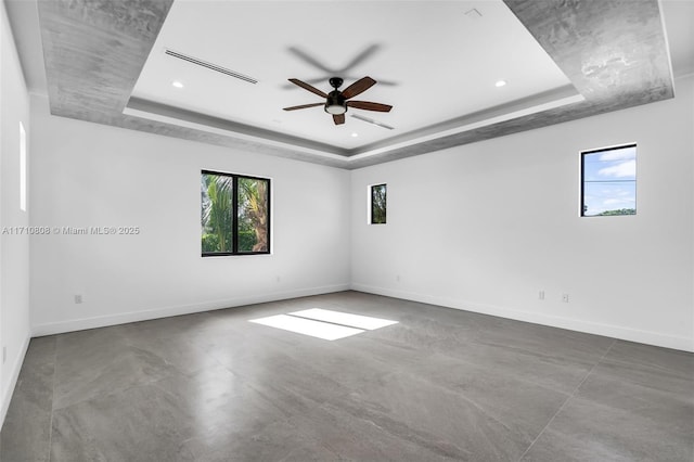 unfurnished room featuring a tray ceiling, concrete flooring, and ceiling fan