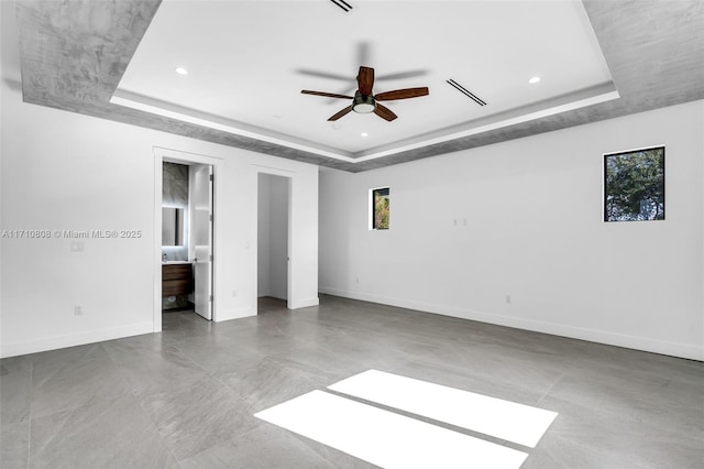 unfurnished bedroom with a raised ceiling, connected bathroom, and ceiling fan