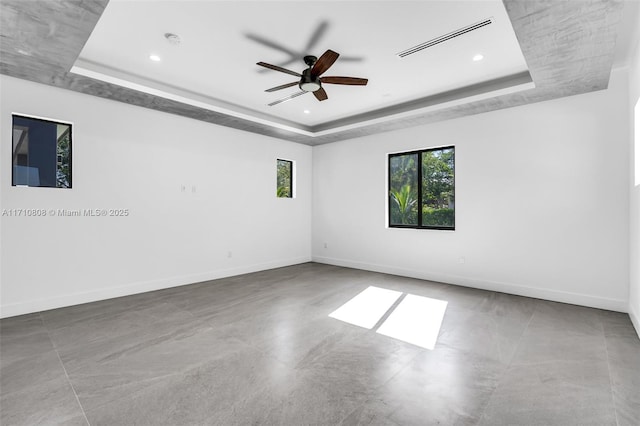 unfurnished room featuring ceiling fan and a raised ceiling