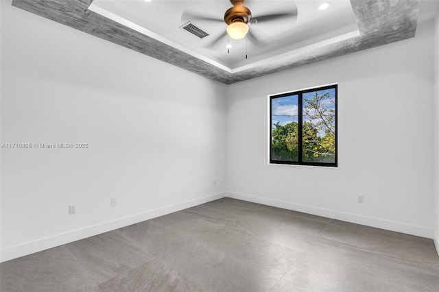 empty room with a tray ceiling and ceiling fan