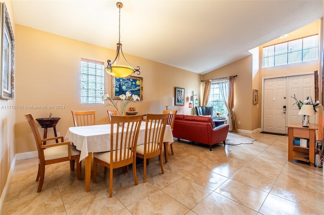 dining room with light tile patterned floors, a healthy amount of sunlight, and lofted ceiling