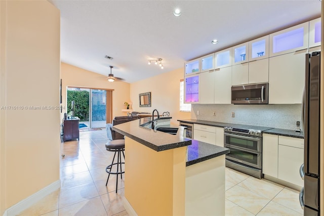 kitchen with sink, vaulted ceiling, a kitchen island with sink, white cabinets, and appliances with stainless steel finishes